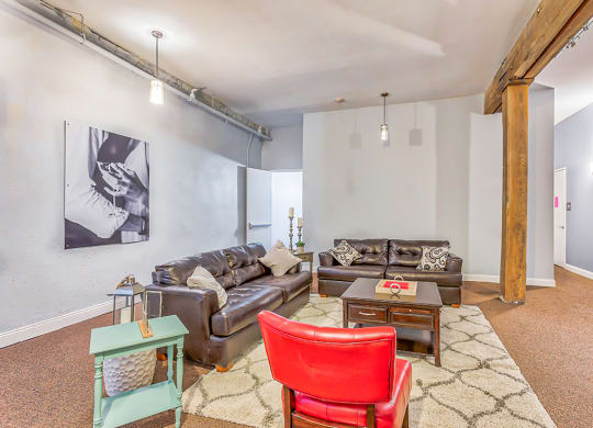 a living room with two leather couches and a red chair