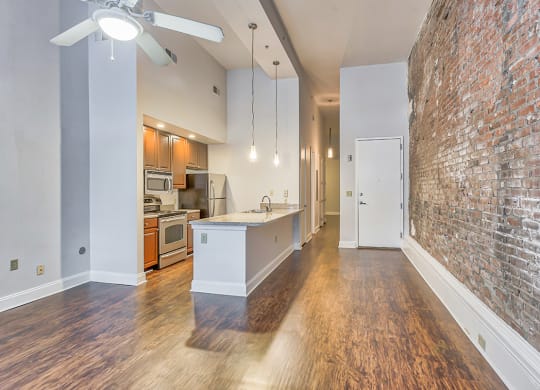 a kitchen and living room with a brick wall and hardwood floors