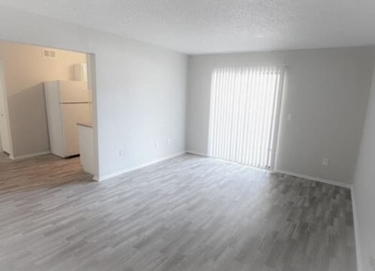 an empty living room with a refrigerator and