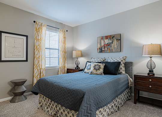 a bedroom with a bed and two lamps and a window