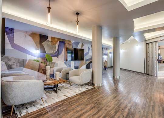 A modern living room with a wooden floor and a large mural on the wall.