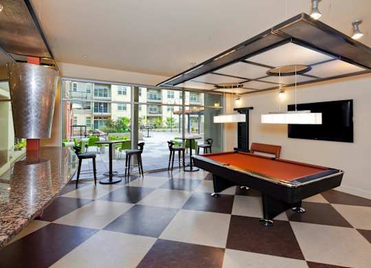 A pool table is in the middle of a room with a checkered floor.