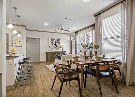 A dining room with a table set for two and a kitchen area in the background.