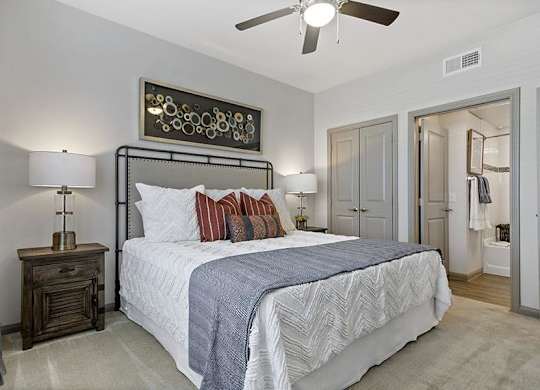 A bedroom with a large bed and a ceiling fan.