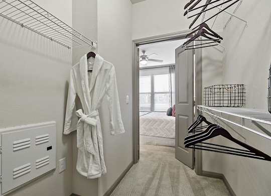 A white robe is hanging on a rack in a room.