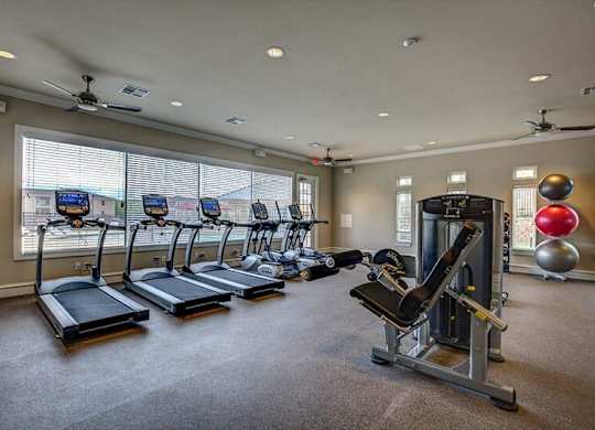 A gym with treadmills, elliptical machines, and a weight machine.