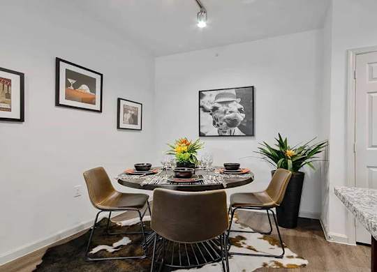A dining room with a table set for four and a cowhide rug.