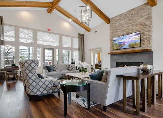 A living room with a stone fireplace and a grey couch.