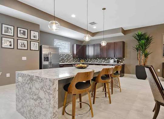 A kitchen with a marble island and wooden chairs.