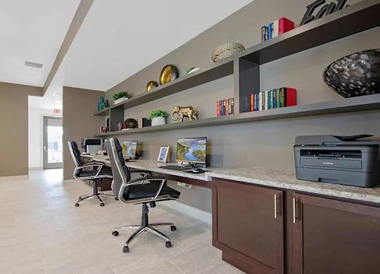 A home office with a desk, chairs, and shelves with decorative items.