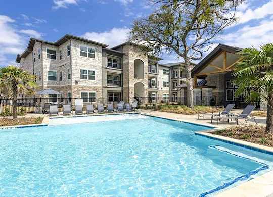 A large swimming pool in front of a multi-story residential building.