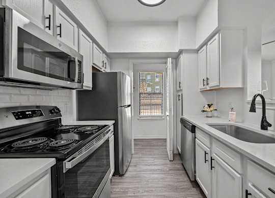 an empty kitchen with white cabinets and stainless steel appliances