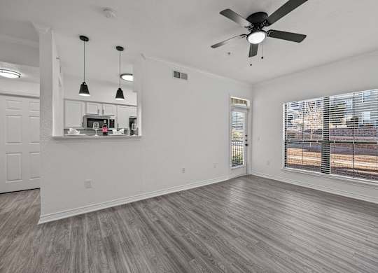an empty living room with a ceiling fan and a window