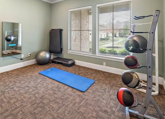 A room with a blue mat and a set of kettlebells.