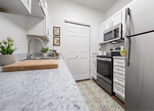 A kitchen with a refrigerator, oven, and sink.