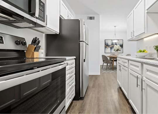 A modern kitchen with black and white appliances and wooden floors.