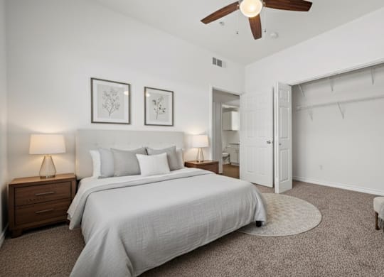 A bedroom with a large bed, a chair, and a ceiling fan.