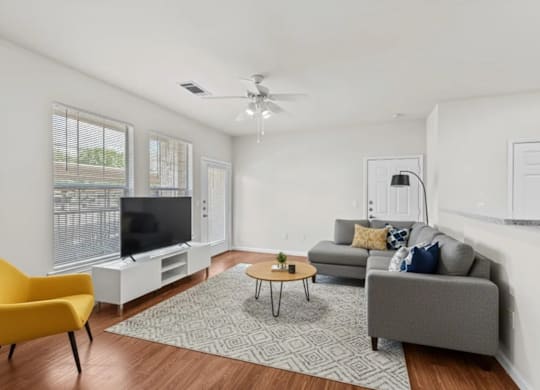 A living room with a yellow chair, grey couch, and a television.