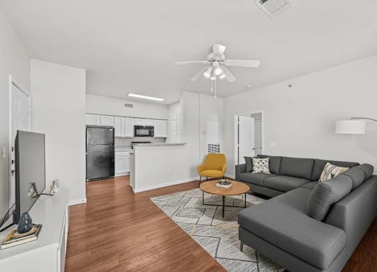 A living room with a grey couch, a yellow chair, and a wooden floor.