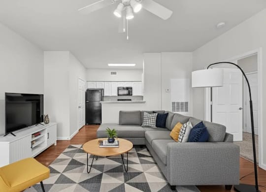 A living room with a grey couch, a yellow chair, a coffee table, and a television.