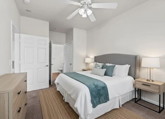 A bedroom with a bed, nightstand, and a ceiling fan.