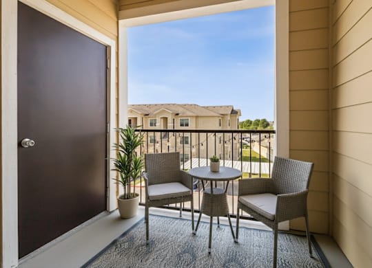 A patio with a table and chairs overlooking a building.