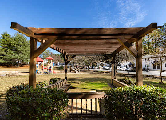 a pergola in a park with a playground in the background
