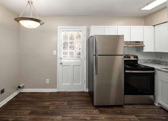 a kitchen with white cabinets and a stainless steel refrigerator