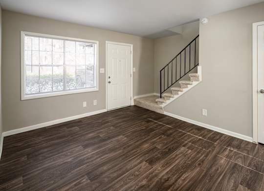 a bedroom with hardwood floors and a staircase