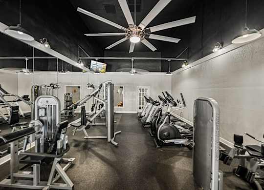 A gym with a variety of equipment including weights and cardio machines.