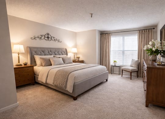 A bedroom with a large bed and a chair by the window.
