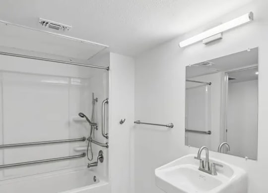 A white sink is mounted on a wall next to a glass shower stall.