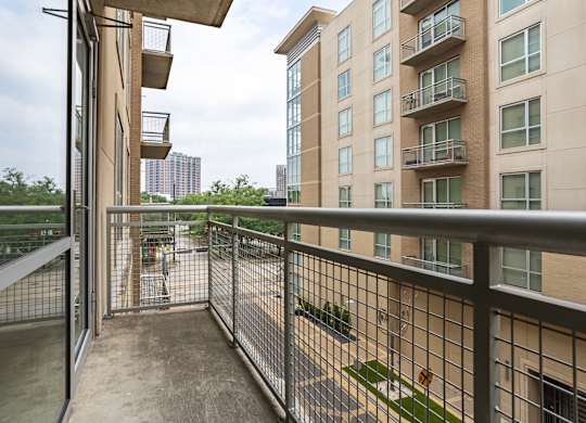 A balcony with a metal railing and a view of a cityscape.