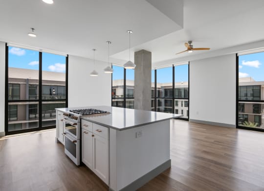 an open kitchen with a large island and a view of a building and windows