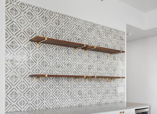 a living room with white cabinets and a wall with a white and white geometric wallpaper