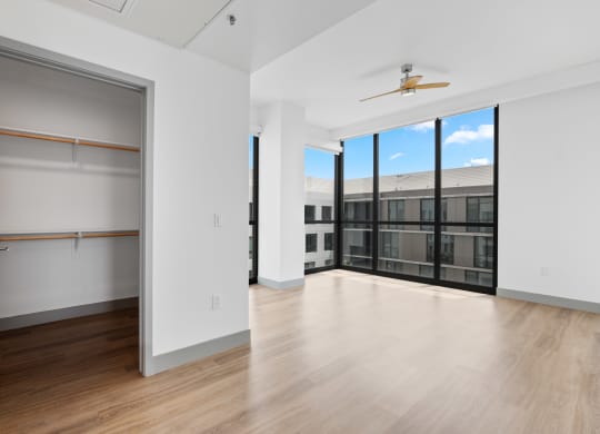 an empty living room with wood flooring and large windows