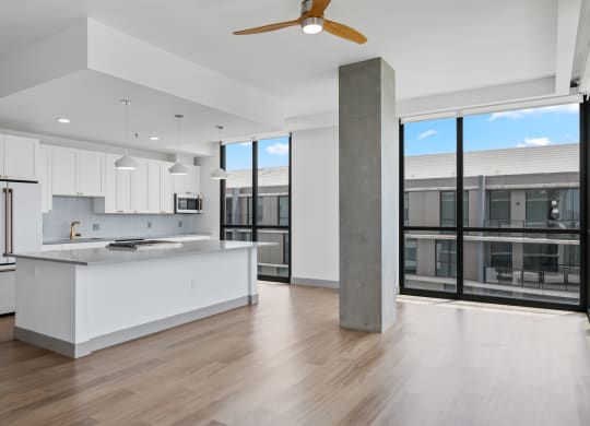 a white kitchen with a large island and a large window