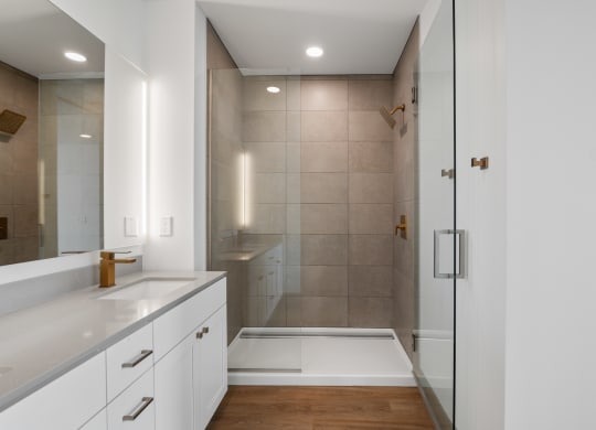 a bathroom with white cabinets and a shower and a sink