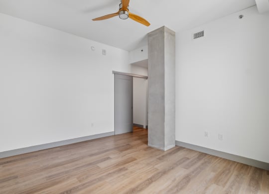 a living room with white walls and wood floors and a ceiling fan