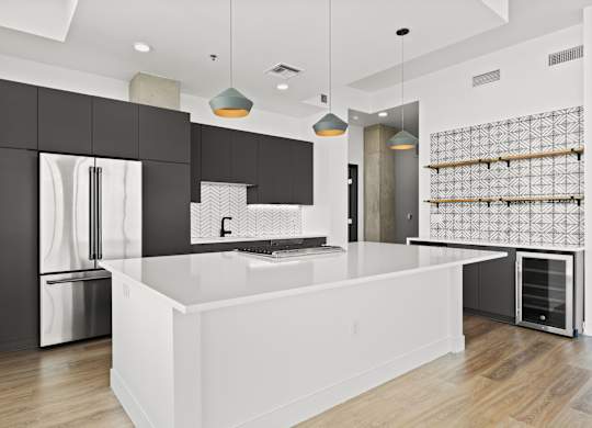 A modern kitchen with a white island and black cabinets.