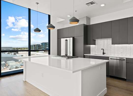 A modern kitchen with a large island and a view of the city.
