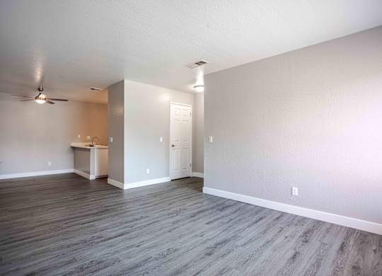 an empty living room with wood floors and a ceiling fan