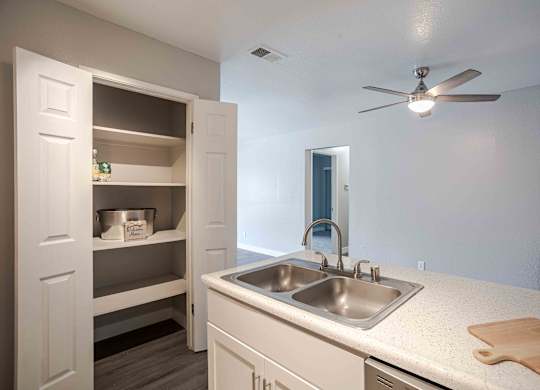 a kitchen with a sink and a ceiling fan