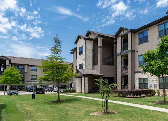 A sunny day at a residential complex with apartment buildings and green lawns.