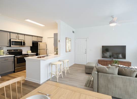 A modern kitchen with a breakfast bar and a grey couch.