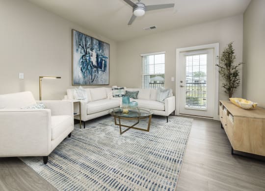 a living room with white couches and chairs and a rug
