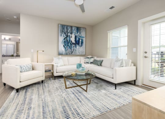 a living room with white couches and chairs and a rug