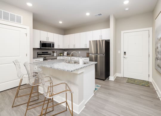 a kitchen with white cabinets and a marble counter top and a stainless steel refrigerator