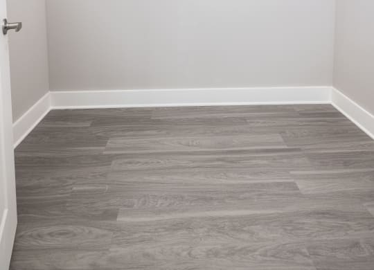 an empty closet with white walls and wood flooring