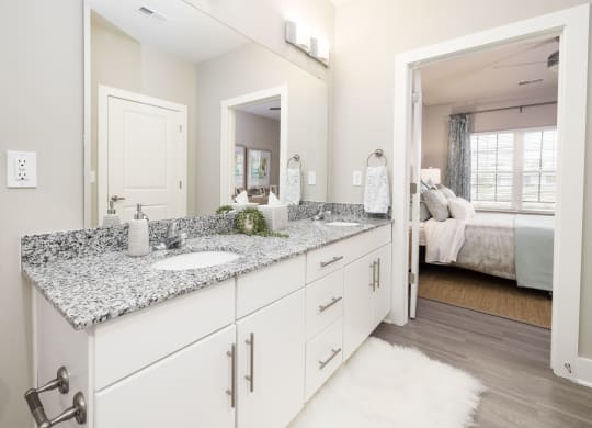 a white bathroom with granite counter tops and a large mirror